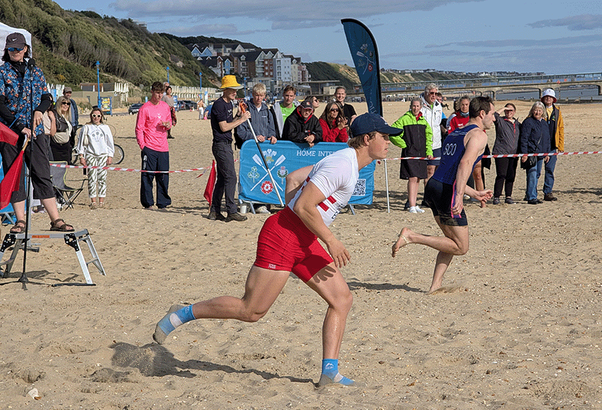 2 male scullers sprinting down beach