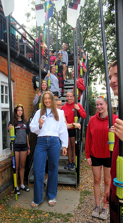 Woman with olympic silver medal and club members holding blades